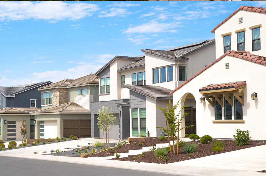 Row of modern suburban houses in Tampa Bay, FL, with varied designs, featuring clean lines and contemporary architecture. The homes are surrounded by landscaped yards and a clear blue sky above.